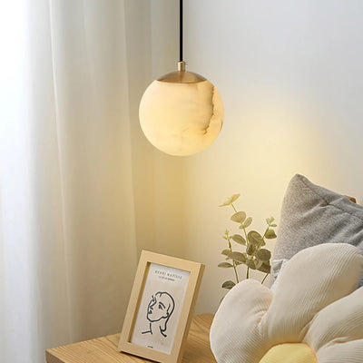 Alabaster pendant glowing at 2700K beside soft curtains