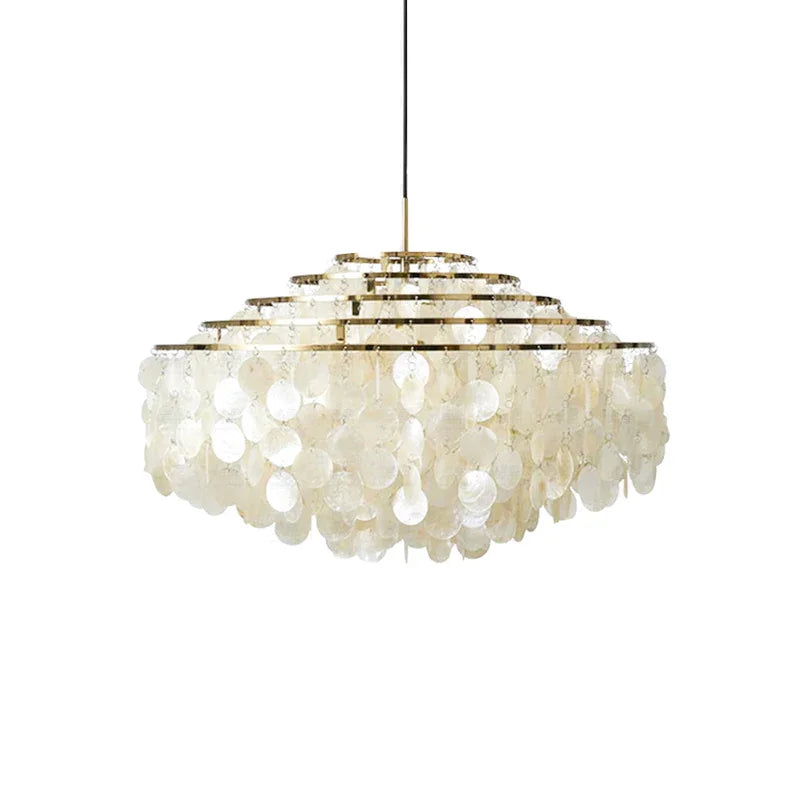 Natural tiered capiz shell pendant light in a gold and white finish hanging over a dining table.
