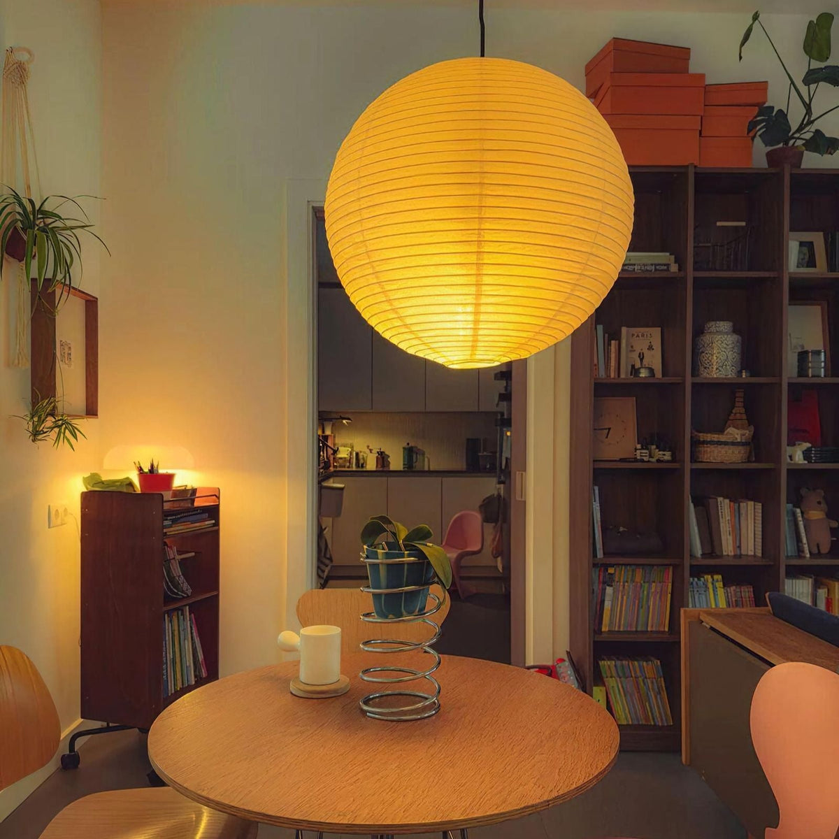 Paper lantern glowing over a warm dining nook at dusk